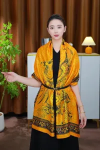 Detailopname van het traditionele fenikspatroon op een luxe oranje zijden sjaal op model.