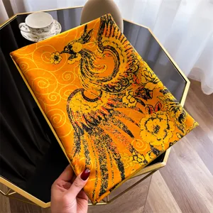 Detailweergave van gele zijden sjaal met elegant zwart feniks- en wolkenpatroon