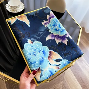 Close-up van een vintage zijden sjaal met een blauw bloemmotief en gouden accenten