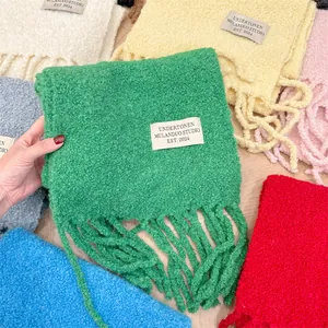 Detalle de bufandas de mezcla de lana bouclé en varios colores con parche bordado