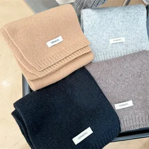 Close-up detail of 100% wool labels on high-quality knitted winter scarves in multiple colors.