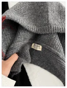 Detalle del pasamontañas de punto gris con etiqueta de marca y textura suave.