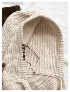 Detalle de un pasamontañas de punto blanco crema con intrincados detalles de costura.