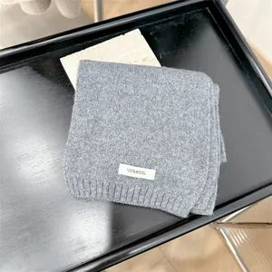 Detailed texture of folded grey 100% wool knit scarf on elegant black tray