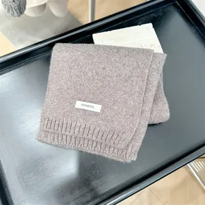 Detailed view of taupe 100% wool knitted scarf showing the premium texture and tag