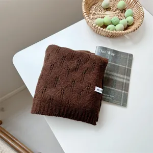 Primer plano de una bufanda de punto marrón oscuro con textura en una mesa blanca