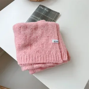 Primer plano de bufanda de lana rosa tejida con calados delicados y etiqueta wool