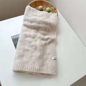 Vista detallada de bufanda de lana de punto crema con textura de patrones y etiqueta de lana
