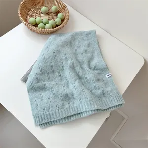 Primer plano de una bufanda de punto verde menta sobre un decorado de mesa blanco