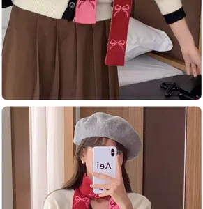 Vue détaillée de l'écharpe en tricot rouge à motifs nœuds présentée dans un selfie miroir stylé