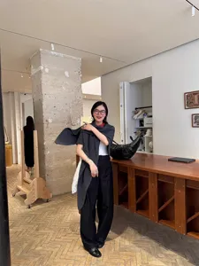 Modell stylt ein dunkelgraues Dreieckstuch aus reiner Wolle in einer modernen Boutique-Umgebung
