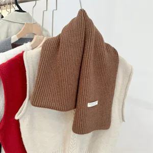 Gedetailleerde weergave van een bruine wollen sjaal met een minimalistisch handgemaakt label