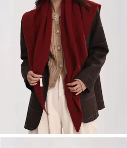 Detailansicht eines roten Schals aus 100% Wolle, getragen über einem karierten Blazer.