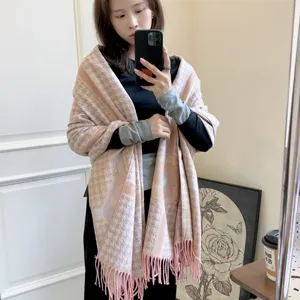 Dettaglio di una sciarpa rosa in finto cashmere con motivo pied-de-poule, camelia e nappe.
