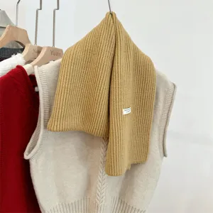 Gedetailleerd overzicht van een gele geribbelde wollen sjaal met een beige gebreid vest.