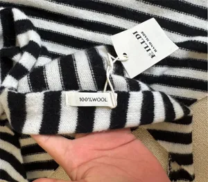 Makro-Detail eines schwarz-weiß gestreiften Wollschals aus 100 % Wolle mit Etikett