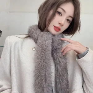 Detailed view of a slim grey faux fur scarf worn by a model for a cozy winter look