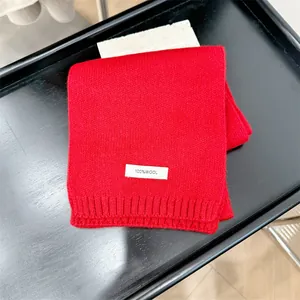 Close-up detail of a bright red 100% wool knitted scarf showing premium soft texture