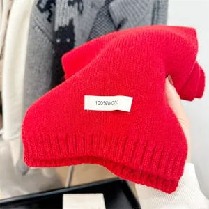 Detail of bright red 100% wool knitted scarf showing the fabric label and texture