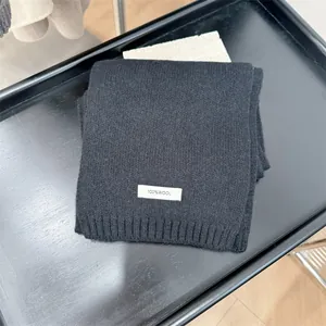 Close-up of black 100% pure wool knitted scarf with a white minimalist material label