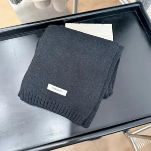 Close-up detail shot of 100% wool black knitted scarf with white material label