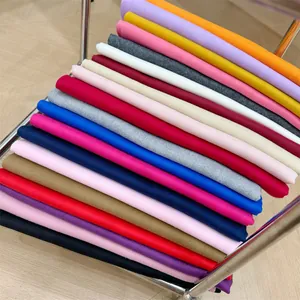 Primer plano de una pila de bufandas de cachemira en varios colores sólidos vibrantes.