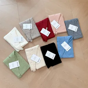 Selection of multi-colored wool knit triangular headscarves arranged on wooden floor surface