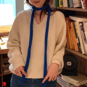 Vue détaillée d'une longue écharpe en maille chenille bleue portée avec un pull blanc