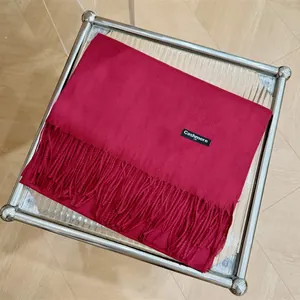 Detalle de una bufanda de cachemira roja premium con flecos en un soporte moderno