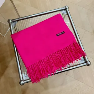 Bufanda de cachemira rosa fucsia con elegantes flecos mostrada sobre la mesa.