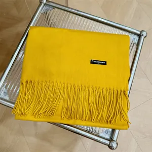 Vista detallada de una bufanda de cachemira amarillo vibrante con elegantes flecos