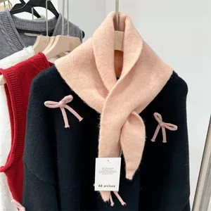 Detailed macro view of a soft pink wool knit triangle scarf featuring a brand tag