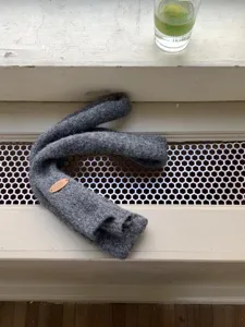 Primer plano de una bufanda gris de punto hecha a mano con etiqueta de cuero decorativa