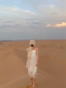 Sciarpa protettiva solare beige in lino indossata da una modella in un paesaggio desertico