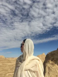 Donna indossa scialle protettivo beige effetto lino come foulard nel deserto