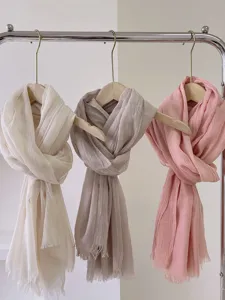 Morbide sciarpe effetto lino in crema grigio e rosa appese a un supporto per l'esposizione