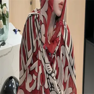 Detail des rot-weißen Kapuzenschals mit traditionellen Knebelknöpfen zum Sonnenschutz.
