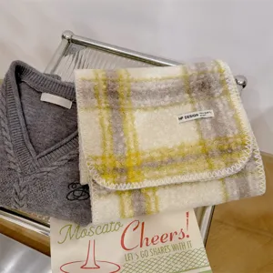 Dettaglio di una sciarpa in lana a quadri gialli e bianchi con un maglione grigio