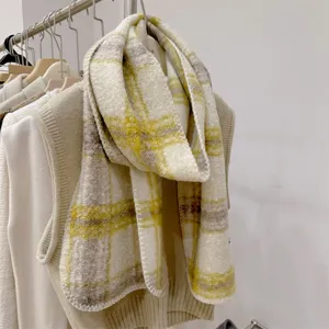Dettaglio di sciarpa in lana a quadri gialla e beige su un appendiabiti elegante