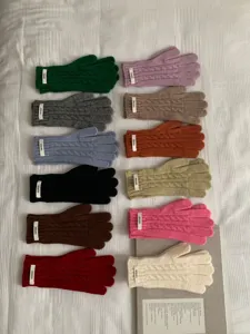Panoramica di guanti invernali in maglia a trecce colorati con etichette Naneys su bianco.