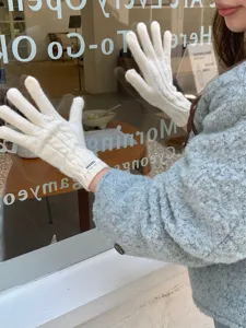 Dettaglio ravvicinato di eleganti guanti in lana intrecciata bianca con marchio