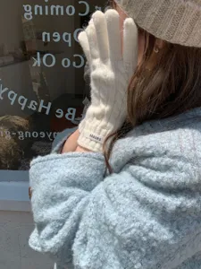 Dettaglio di guanti bianchi in maglia a trecce da donna per calore e stile invernale