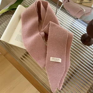 Primer plano del tejido de punto rosa suave y la etiqueta Trendy de una bufanda estrecha