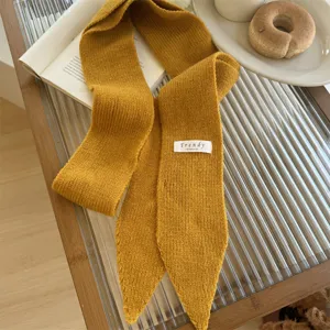 Detalle de primer plano de una bufanda de punto estrecha amarillo mostaza con etiqueta