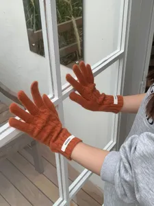 Primo piano dettagliato di comodi guanti in maglia a trecce arancioni per l'inverno