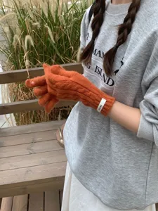 Dettaglio dei guanti in maglia a trecce arancioni senza dita per l'inverno
