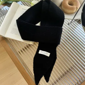 Vista detallada de una elegante bufanda de punto estrecha negra con etiqueta blanca Trendy
