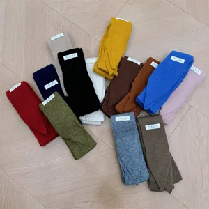 Surtido de bufandas de punto estrechas multicolores con etiquetas en suelo de madera