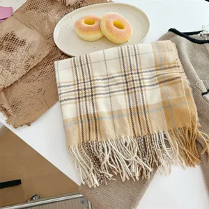 Detailansicht eines warmen Karoschals mit Fransen in eleganten Beige- und Gelbtönen
