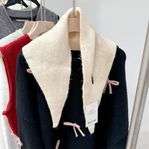 Detail of cream wool knit triangle scarf with brand hangtag on a clothing rack